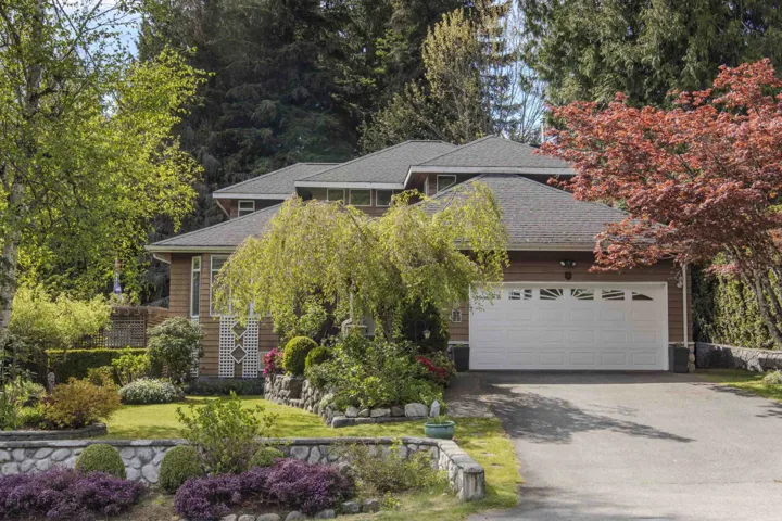 Wood-sided residence featuring a multi-level roofline and a white garage door with decorative window inserts