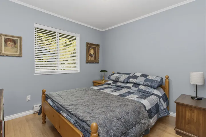 Room featuring light blue walls, wood-finish flooring, white baseboards, and crown molding