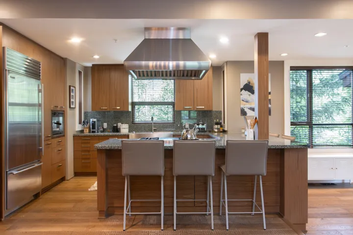 Kitchen with built in refrigerator, island range hood, light wood-style floors, a peninsula, and recessed lighting