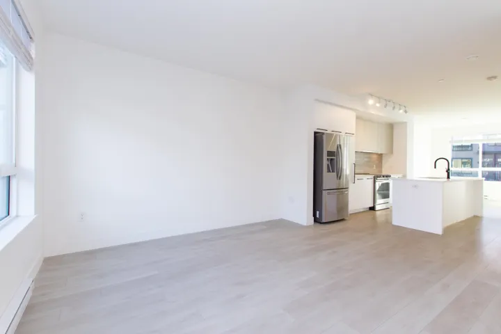 Kitchen featuring a baseboard radiator, stainless steel appliances, an island with sink, open floor plan, and light wood-style floors