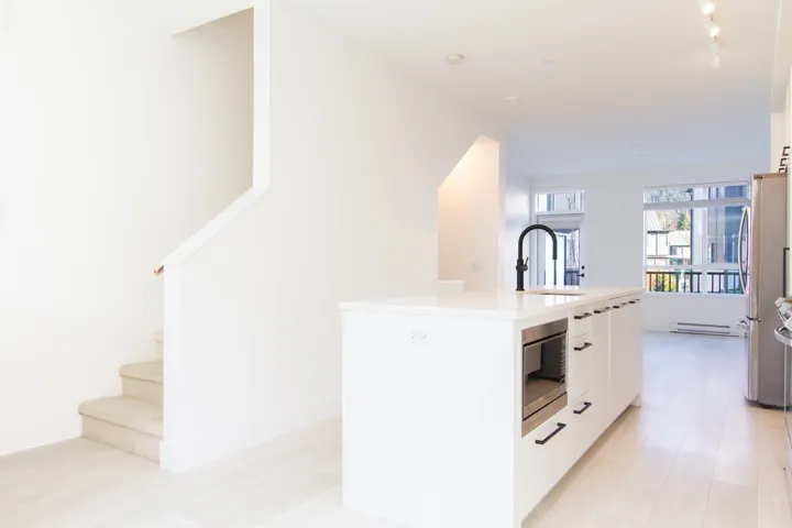 Kitchen with white cabinetry, a center island with sink, appliances with stainless steel finishes, modern cabinets, and a baseboard heating unit