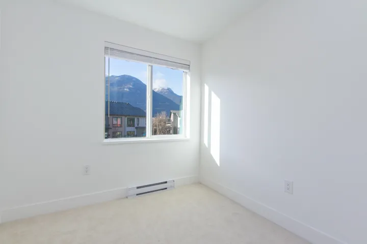 Unfurnished room featuring a mountain view, baseboard heating, and light colored carpet