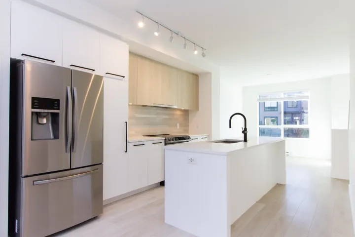 Kitchen with stainless steel appliances, modern cabinets, backsplash, and a kitchen island with sink