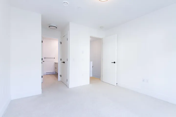 Unfurnished bedroom featuring light carpet and connected bathroom