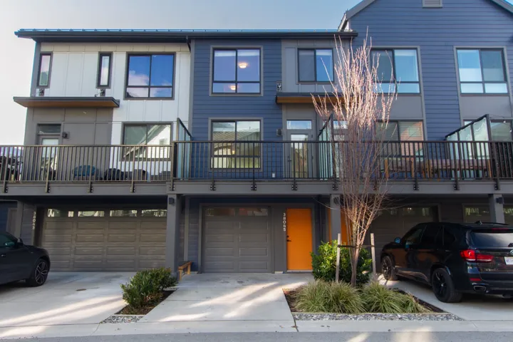 View of front of house with driveway, a garage, and a balcony