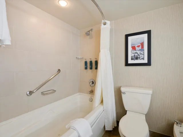 Bathroom featuring wallpapered walls, shower / tub combo with curtain, and toilet