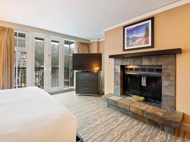 Carpeted bedroom with baseboards and a tiled fireplace