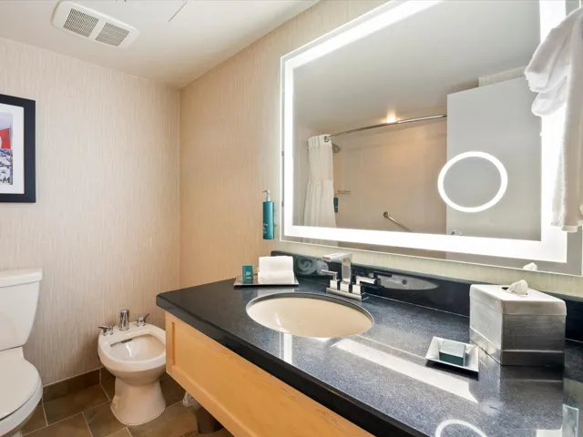 Full bathroom with wallpapered walls, vanity, curtained shower, toilet, and visible vents