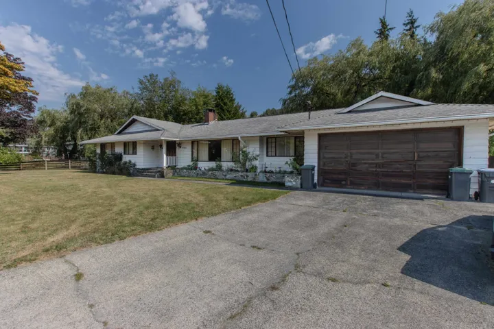 Ranch-style home with asphalt driveway, a chimney, a porch, and a garage