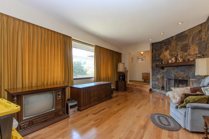 Living area featuring a stone fireplace, light wood-style flooring, and recessed lighting