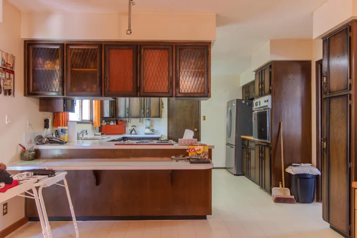 Kitchen with a peninsula, light countertops, a breakfast bar, freestanding refrigerator, and light floors