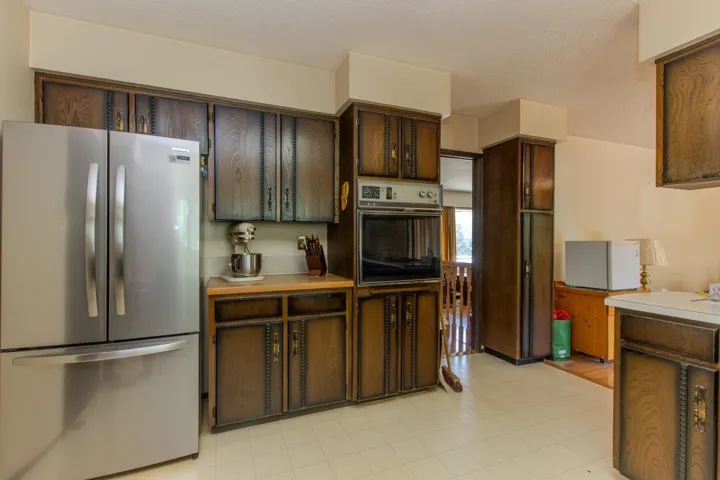 Kitchen featuring freestanding refrigerator, light countertops, a textured ceiling, and dark brown cabinetry