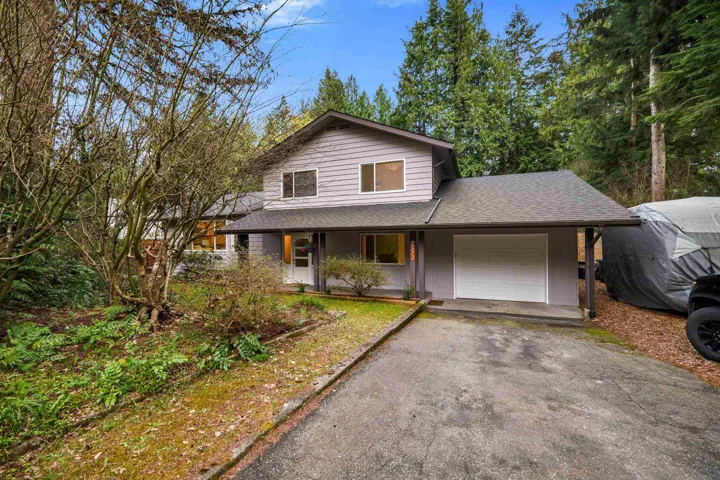 View of front of home with a shingled roof, covered porch, driveway, and a garage