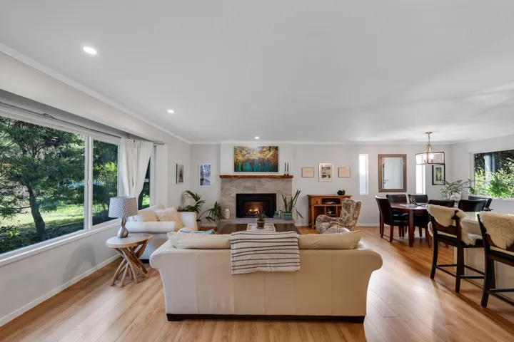 Living area featuring light wood-type flooring, recessed lighting, a warm lit fireplace, and ornamental molding