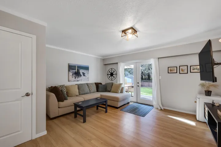 Living room featuring french doors, light wood finished floors, ornamental molding, and a textured ceiling