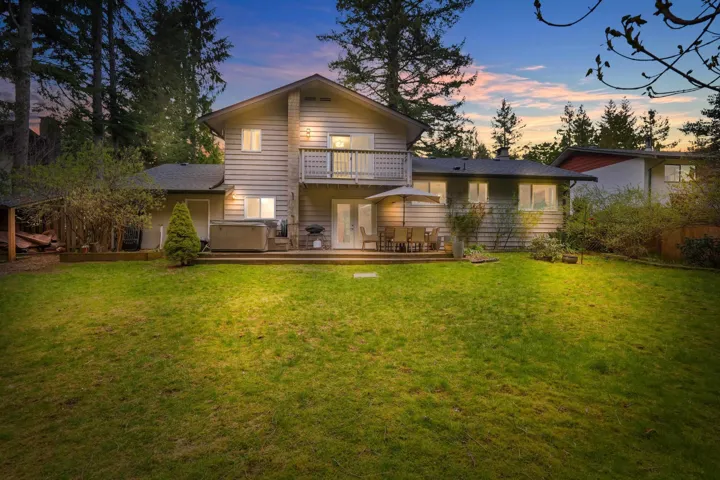 Expansive backyard featuring a large lawn, multi-level decking, and a second-story balcony
