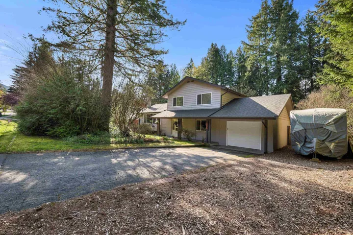 Traditional home featuring a shingled roof, driveway, a garage, and covered porch