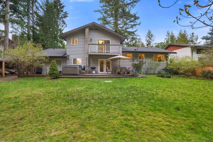 Rear view of house featuring a hot tub, french doors, a wooden deck, and a balcony
