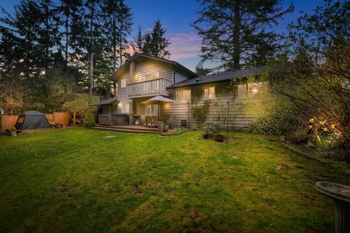 Back of property at dusk with a balcony and a deck