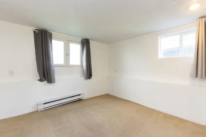 Unfurnished room with a baseboard heating unit, carpet floors, and plenty of natural light