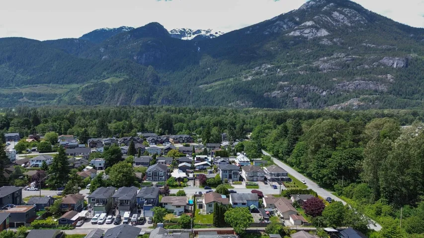 Aerial view of property and surrounding area featuring a mountainous background and nearby suburban area