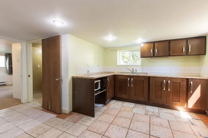 Kitchen featuring white microwave, dark brown cabinetry, and tasteful backsplash