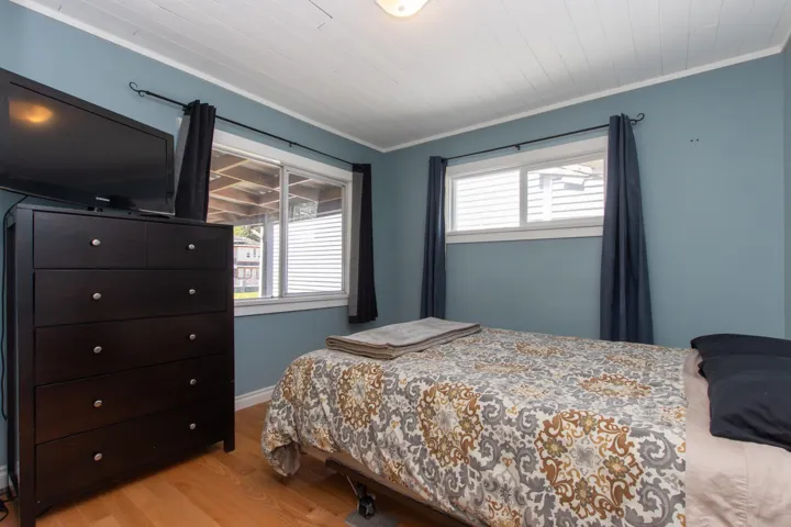 Bedroom with light wood-style flooring, crown molding, and multiple windows