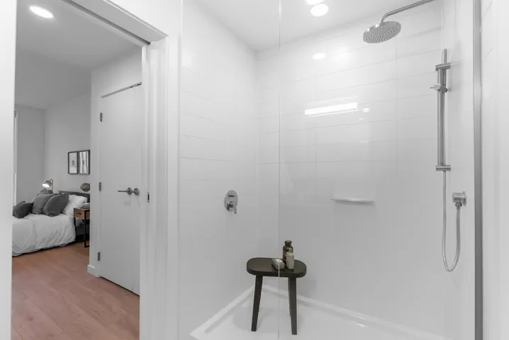 Bathroom with ensuite bathroom, tiled shower, wood finished floors, and recessed lighting