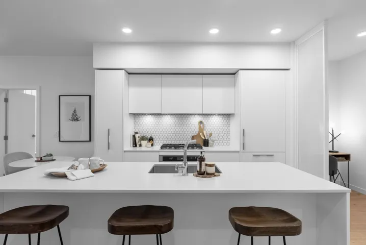 Kitchen featuring white cabinets, a kitchen breakfast bar, a large island with sink, modern cabinets, and light stone countertops