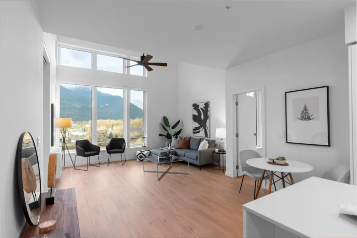 Living room featuring light wood-type flooring, a ceiling fan, a high ceiling, and a mountain view