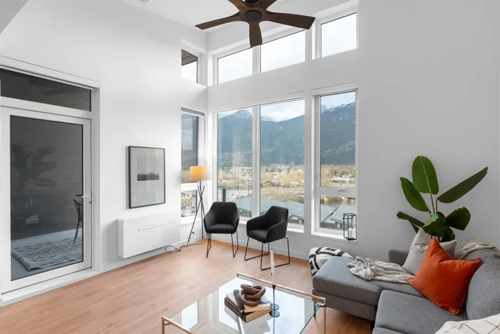 Living room featuring light wood-style flooring, ceiling fan, a high ceiling, and a mountain view