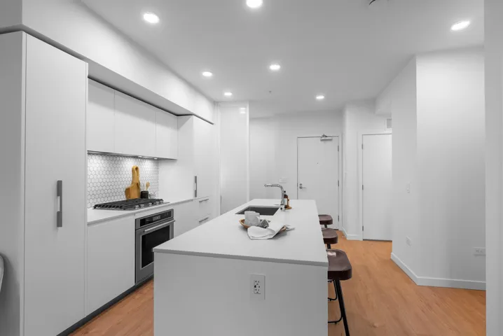 Kitchen with modern cabinets, a kitchen bar, white cabinets, appliances with stainless steel finishes, and a kitchen island with sink