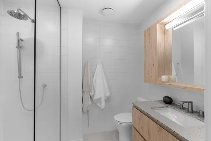 Bathroom with vanity, a shower stall, tile walls, and light tile patterned flooring
