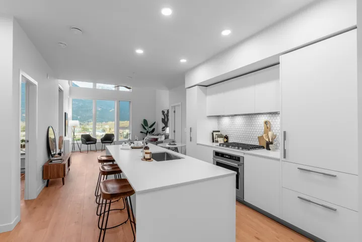Kitchen featuring modern cabinets, white cabinetry, tasteful backsplash, appliances with stainless steel finishes, and open floor plan