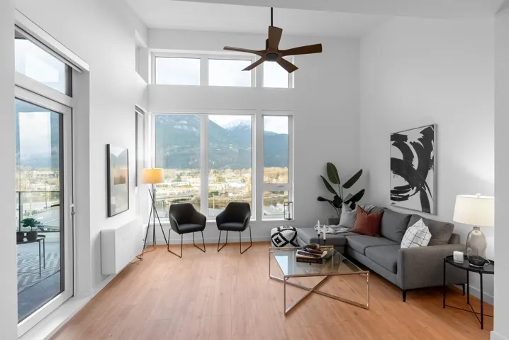 Living room featuring light wood finished floors, radiator, ceiling fan, a high ceiling, and a mountain view