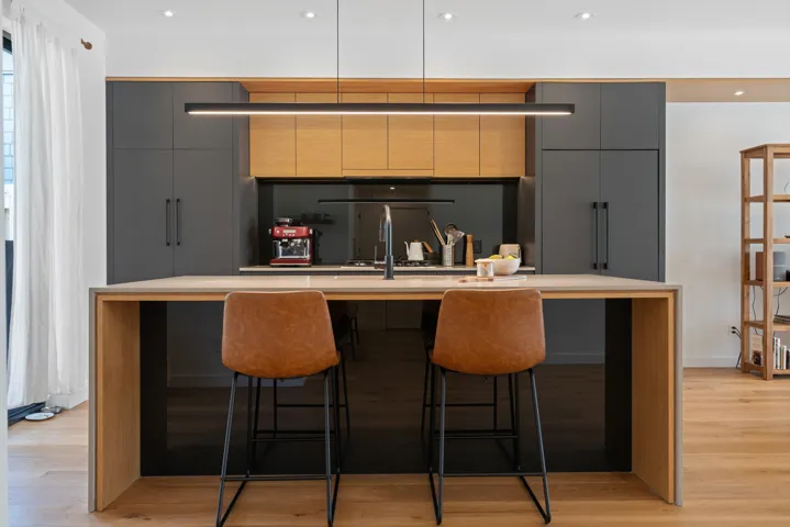 Kitchen featuring light wood-style flooring, a breakfast bar, modern cabinets, a center island with sink, and gray cabinets