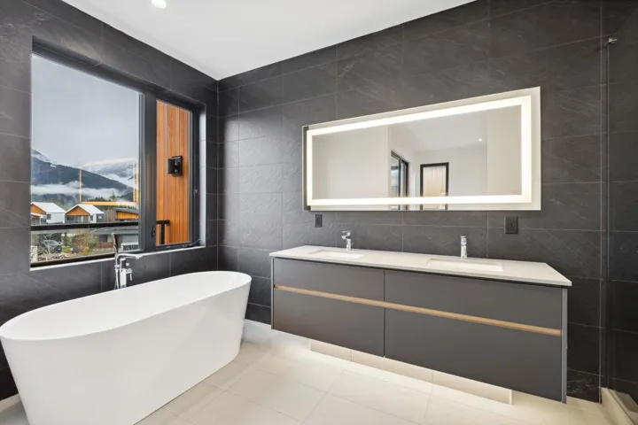 Full bath featuring tile walls, double vanity, a freestanding tub, a mountain view, and light tile patterned flooring