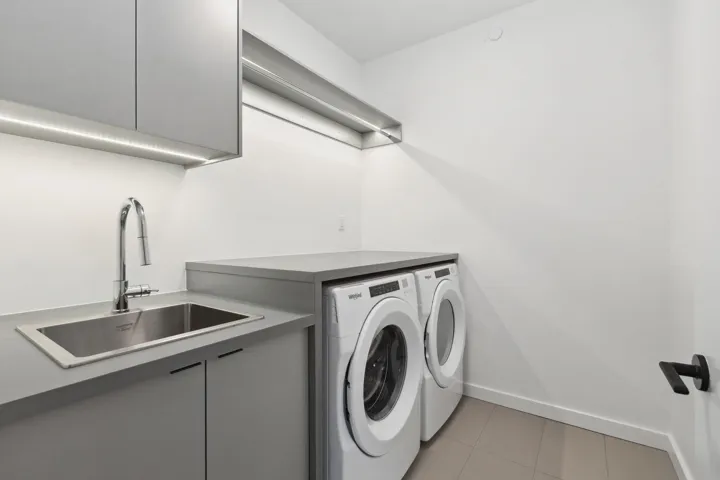Washroom featuring light tile patterned floors, cabinet space, and washing machine and dryer