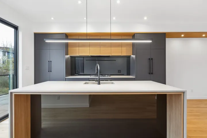 Kitchen with modern cabinets, light stone countertops, light wood-style flooring, a center island with sink, and recessed lighting