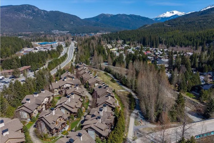 Aerial view of residential area featuring a mountain backdrop and a heavily wooded area