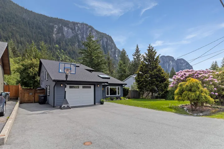 View of front of property with a garage, a mountain view, driveway, a gate, and roof with shingles