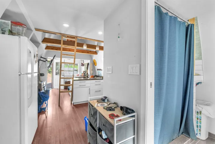 Open-concept interior featuring wood-finish flooring, white cabinetry, and recessed lighting
