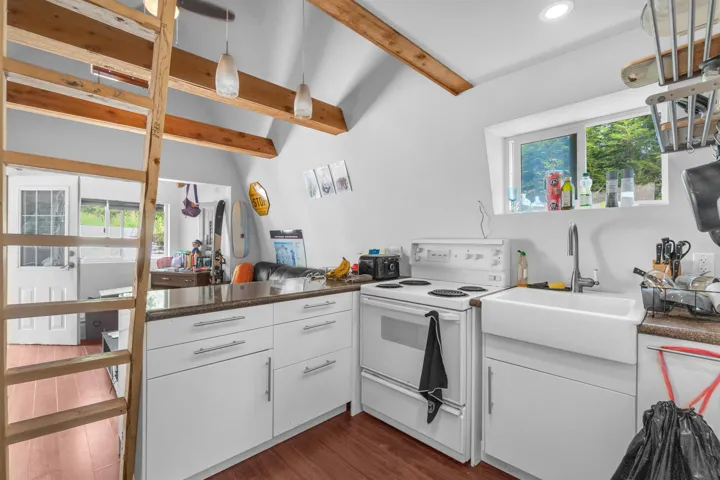 Kitchen features white cabinetry, a farmhouse sink, and a four-burner electric range