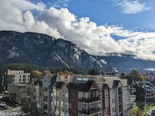 Mountain backdrop with prominent rock faces, featuring surrounding evergreen trees and autumn foliage