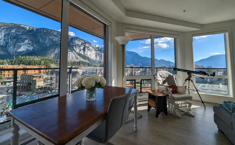Spacious interior featuring large windows, wood-finish flooring, and direct access to a balcony with glass railings