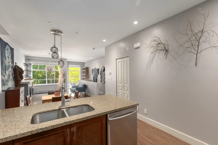 Kitchen island featuring a double basin stainless steel sink, granite-finish countertop, and integrated stainless steel dishwasher