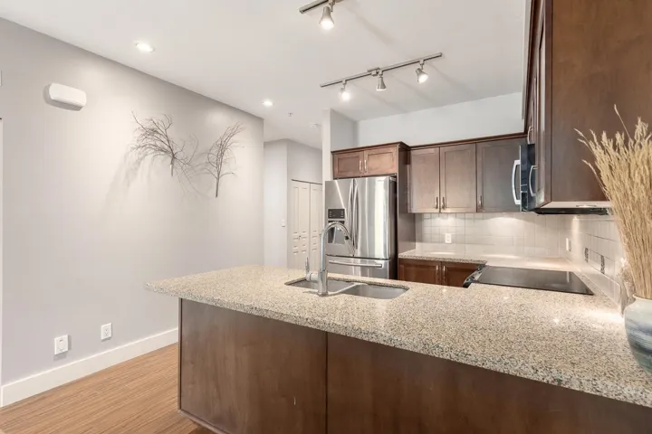 Kitchen island featuring a granite-finish countertop and an undermount stainless steel sink