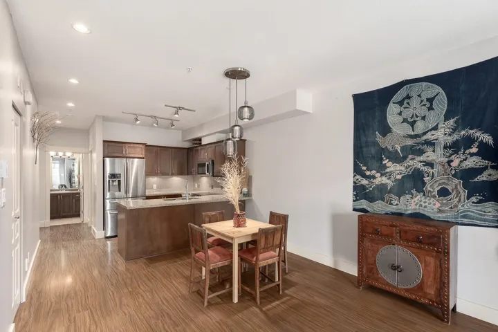 Open-concept kitchen and dining area featuring wood-finish flooring, stainless steel appliances, a kitchen island with a light-toned countertop, and recessed lighting
