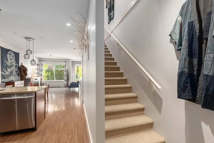 Carpeted staircase with a white handrail, featuring light gray walls