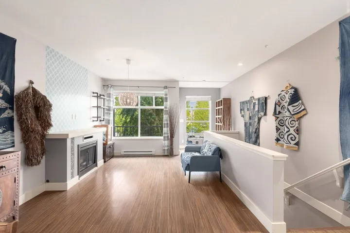 Spacious living area featuring wood-finish flooring, a built-in electric fireplace with a white mantel, and large windows
